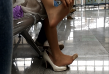 Girl take off heels relax her tired feet when waiting for the train in railway station lounge 