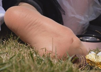 The lady takes off her boots and relaxes her feet on the lawn