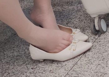 The lady in white heels dipping shoeplay in the waiting hall of the railway station