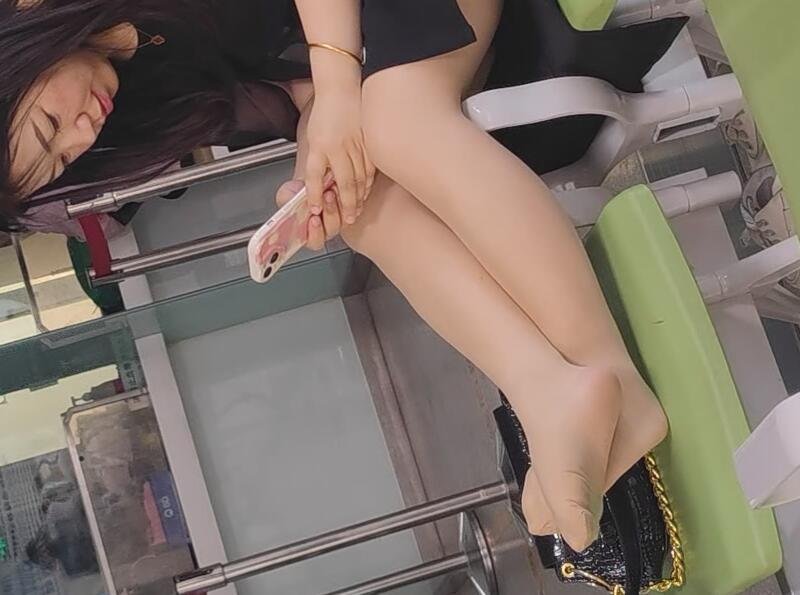 The beautiful girl in stockings playing with her phone on a chair